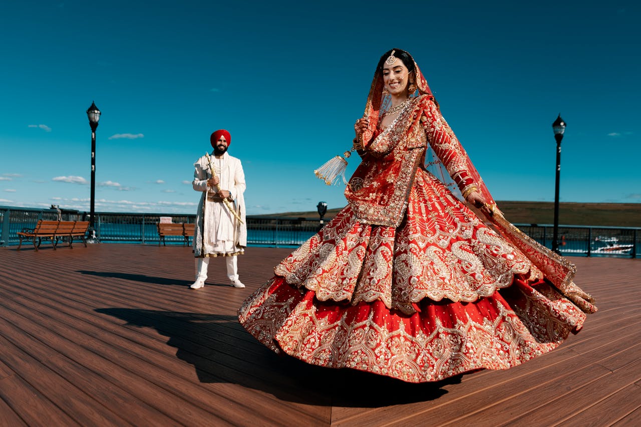 about-us A joyous Indian couple in traditional attire celebrating their wedding outdoors on a sunny day.