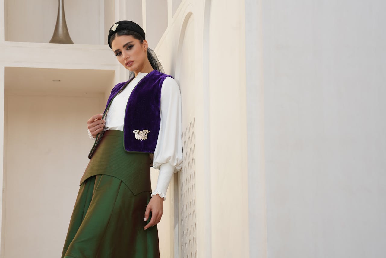 why-choose-us Portrait of a woman in a stylish traditional outfit with a purple vest, indoors.
